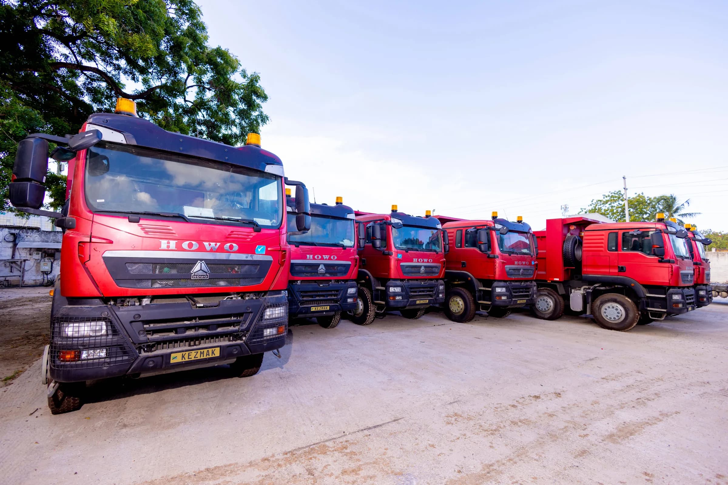 Kezmak's red HOWO truck fleet at the yard